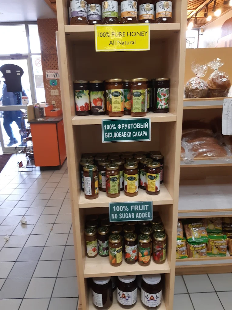 Wooden shelf of glass jars of honey and fruit preserves with natural product signs.