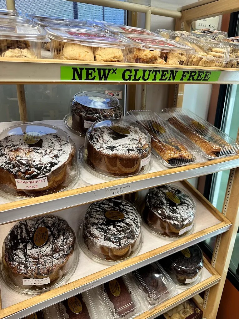 Wooden shelves of packaged cakes including cranberry and chocolate bundt cakes and a gluten-free section.
